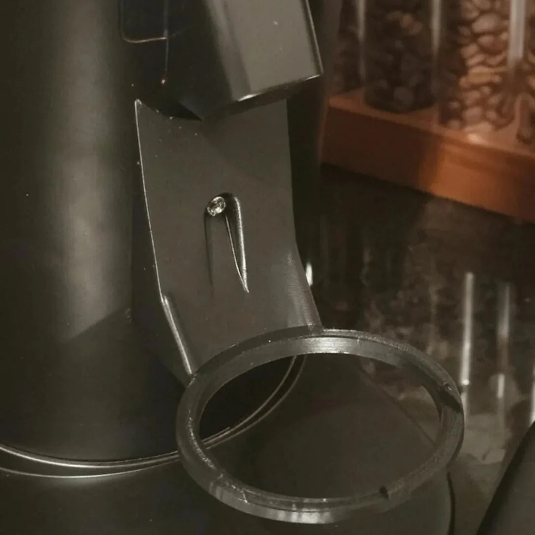 Close-up of a black kitchen appliance with a metal ring on a dark surface.